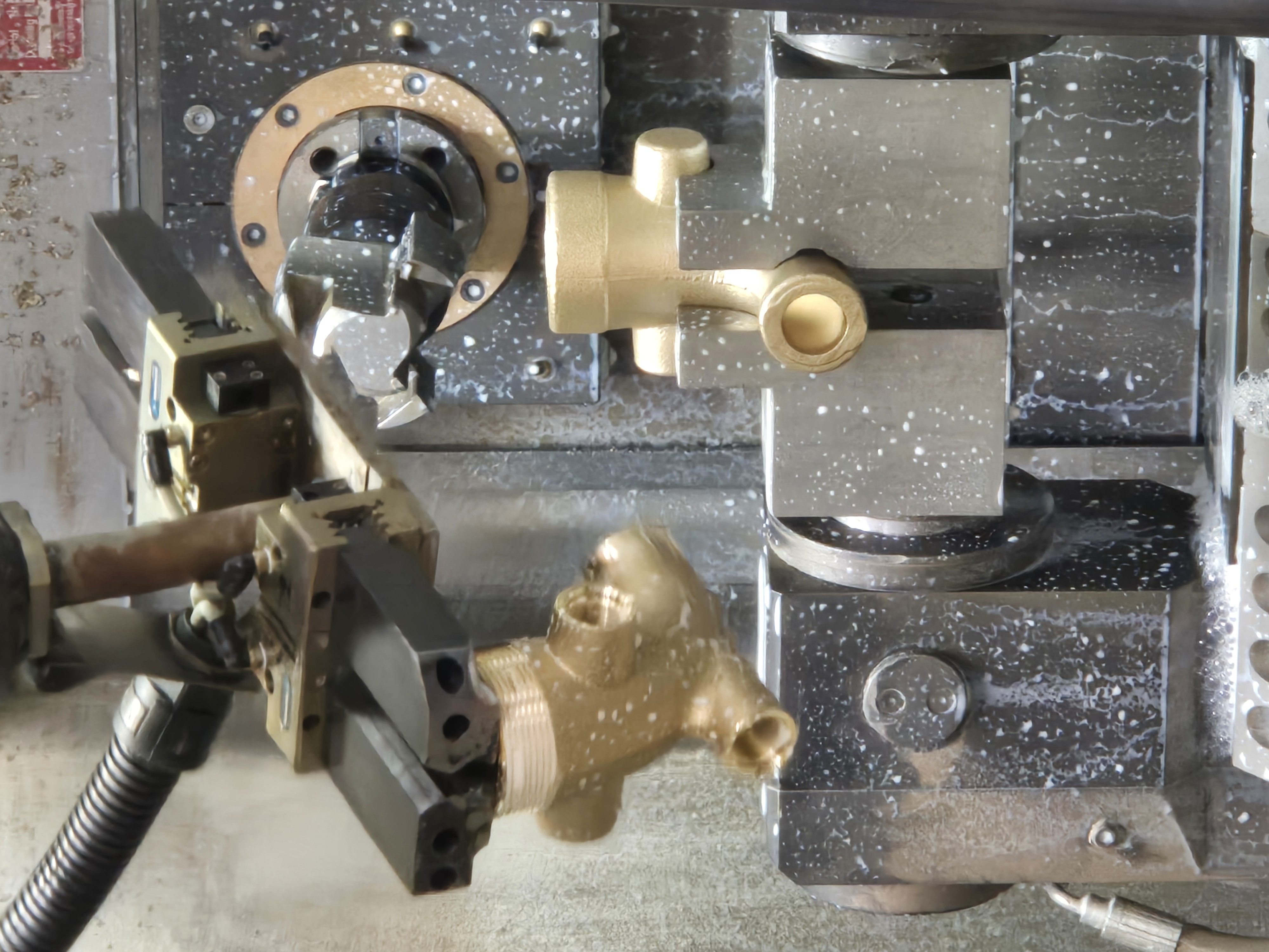 A brass part being machined on a lathe with coolant
